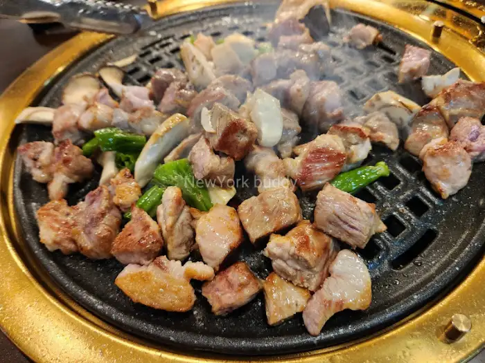 잘 익어가고 있는 두툼한 고기와 버섯이 올라간 불판