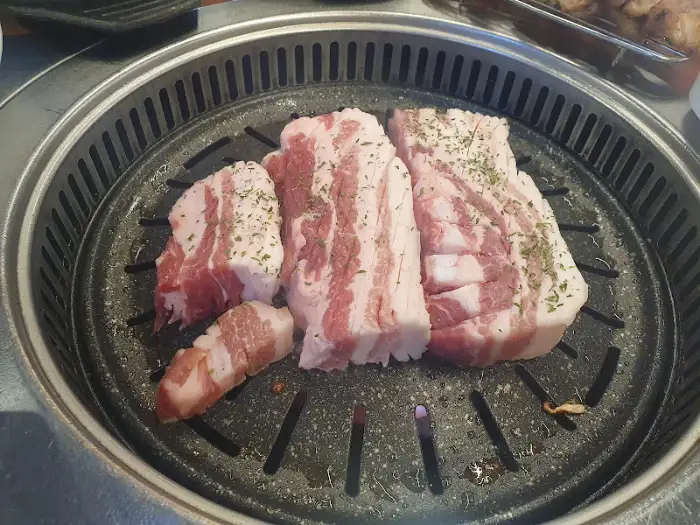 불판 위에 놓인 두툼한 삼겹살 덩어리