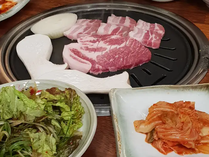 두툼한 삼겹살과 버섯이 숯불 그릴 위에 놓여 구워지는 모습