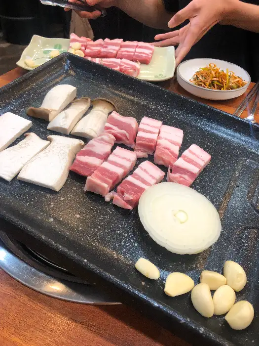 신선한 삼겹살과 버섯, 양파, 마늘이 함께 준비된 모습