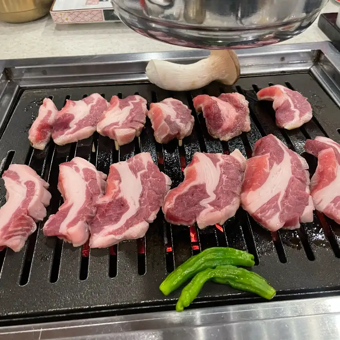 불판 위에서 노릇하게 익어가는 삼겹살과 목살