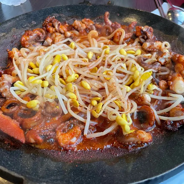 접시에 담긴 쭈꾸미볶음과 콩나물, 양념이 잘 버무려져 있는 모습