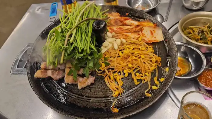 솥뚜껑 위에서 익어가는 삼겹살과 미나리