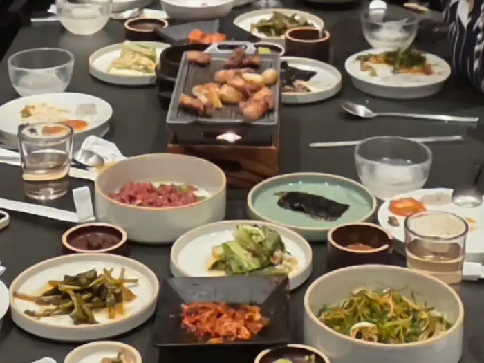 다양한 밑반찬과 고기, 밥, 그리고 국물 요리가 곁들여진 식사 테이블 모습.