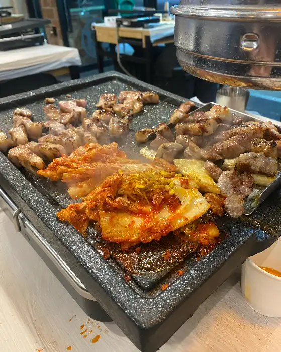 잘 구워진 고기와 김치가 함께 놓여 있는 불판