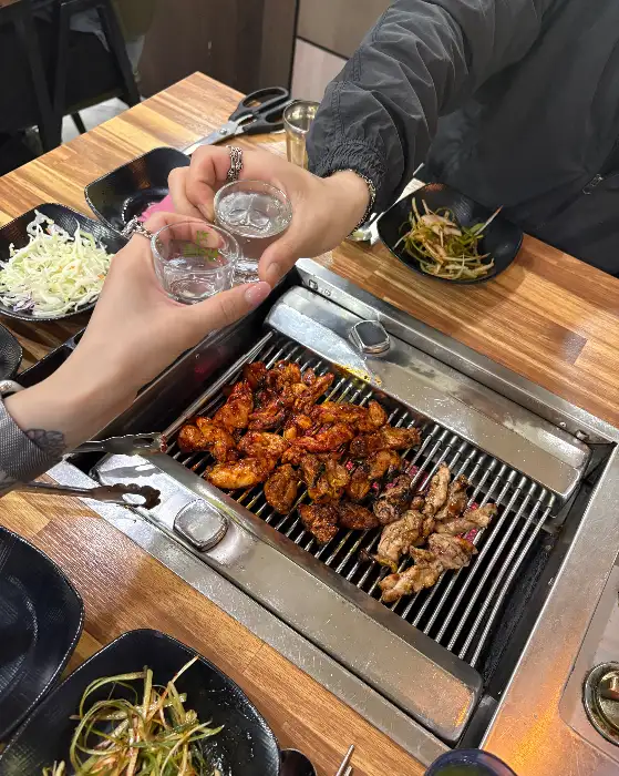 두 사람이 함께 짠하며 닭갈비를 즐기는 모습