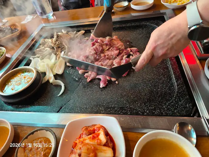 돌판 위 오리 요리를 뒤집으며 익히고 있는 모습