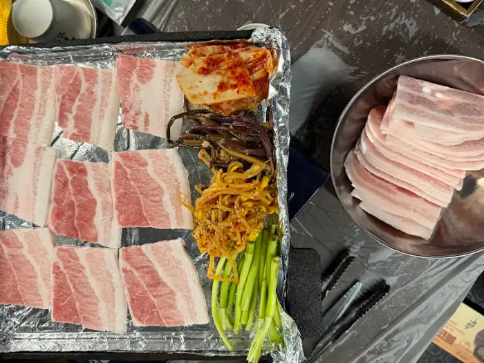 불판에 구워지는 삼겹살과 곁들임