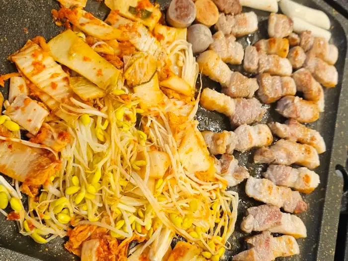돌판 위 푸짐한 삼겹살과 콩나물, 김치