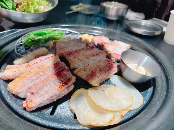 숯불 위에서 익어가는 돼지갈비와 곁들임 채소
