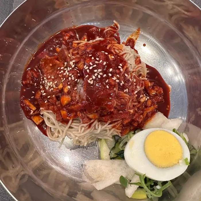 붉은 양념이 듬뿍 올라간 비빔냉면과 삶은 달걀, 오이채