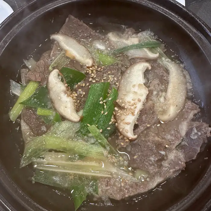 버섯과 파, 고기가 자박한 국물과 함께 끓여지고 있는 전골 냄비