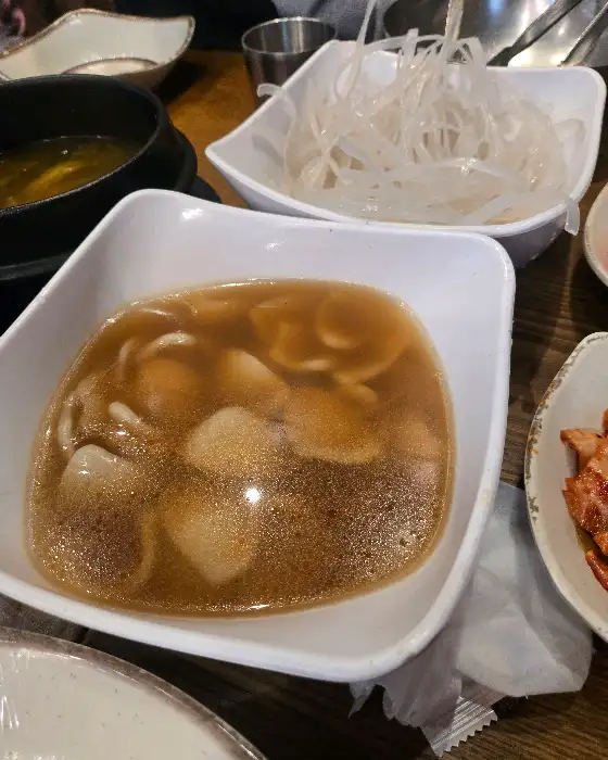 뜨거운 국물 위에 수제비와 파가 띄워져 있습니다.