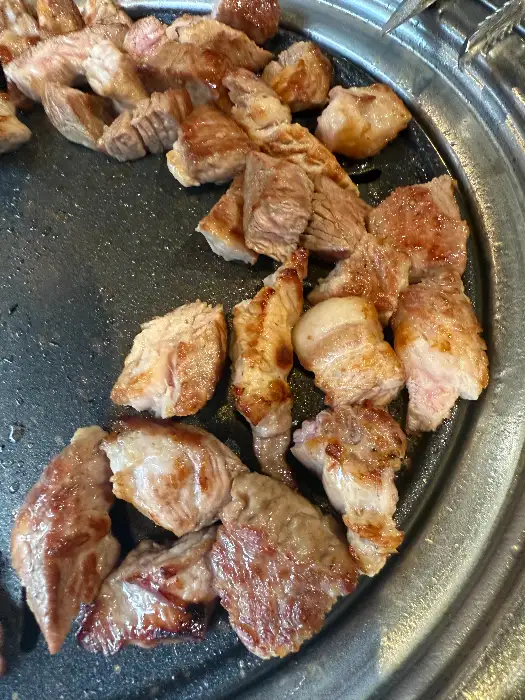 불판 위에서 맛있게 익어가고 있는 삼겹살 조각들