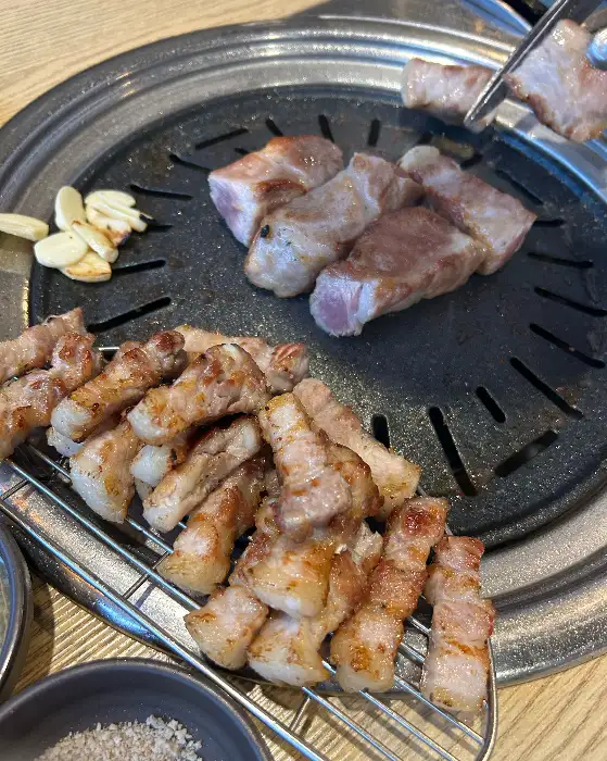 다양한 쌈 채소와 곁들여 먹을 수 있는 마늘, 쌈장, 쌈무 등의 모습