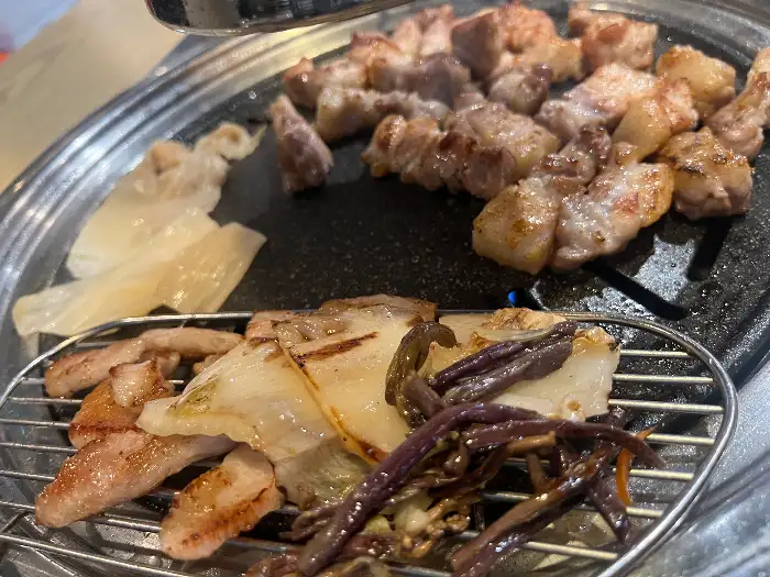 잘 구워진 삼겹살 조각이 곁들임 채소와 함께 올려진 모습
