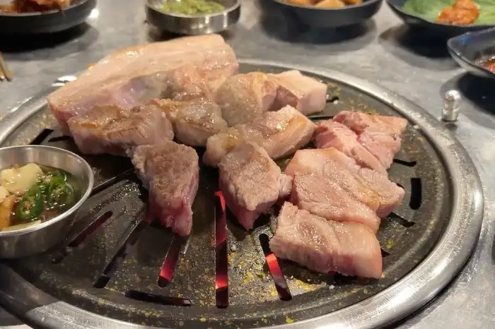 노릇하게 구워진 흑돼지 오겹살과 목살이 불판 위에 가지런히 놓여 있다.