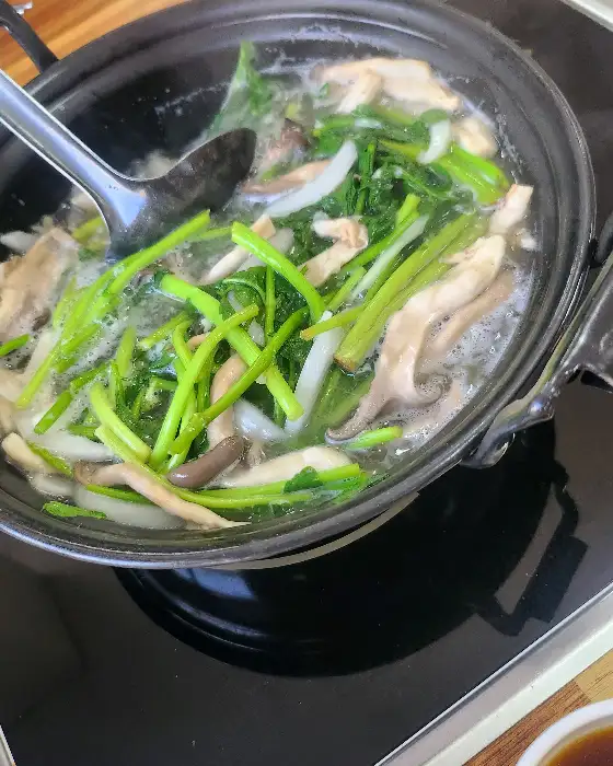 보글보글 끓고 있는 칼국수 냄비 안의 버섯, 미나리, 그리고 국물