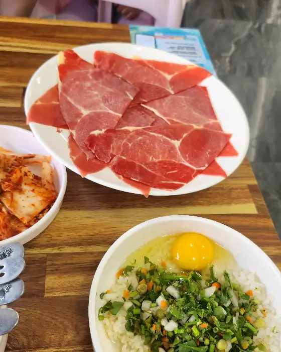 잘 익은 김치와 얇게 썬 소고기, 그리고 밥 위에 계란 노른자와 채소가 올라간 모습