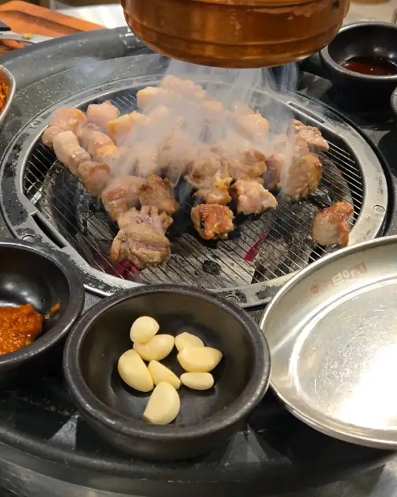 숯불 위에서 맛있게 익어가고 있는 두툼한 돼지고기