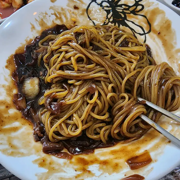 면 위에 진한 간짜장 소스가 넉넉하게 부어져 있는 모습