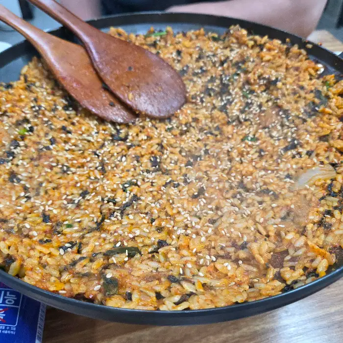 넓은 팬에 볶아진 밥과 김가루, 깨가 뿌려진 모습