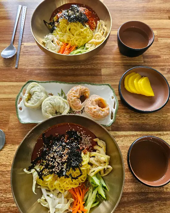 비빔국수와 만두, 곁들임 반찬이 함께 나온 모습
