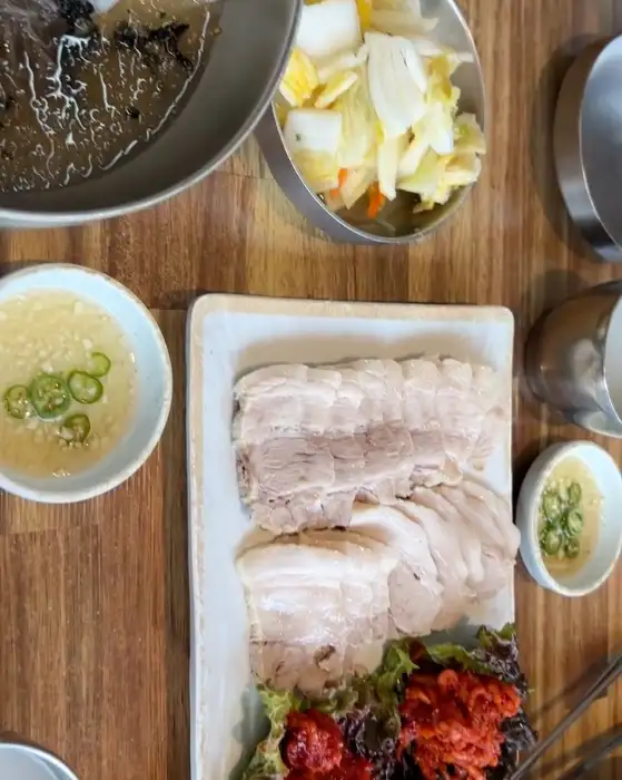수육 조각들 사이에 놓인 채 썬 무와 배추김치