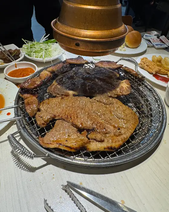 숯불 위에 놓인 두툼한 돼지갈비와 삼겹살 조각들