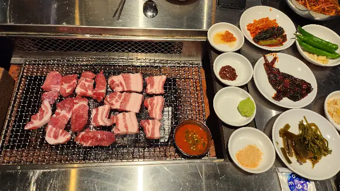 숯불 위에서 익어가는 고기와 함께 차려진 다채로운 반찬들
