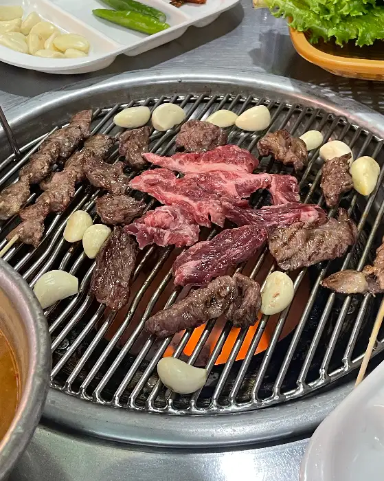 연탄불 위에서 구워지고 있는 다양한 부위의 고기와 마늘