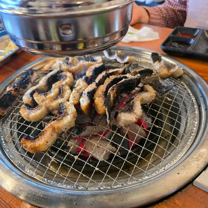 여러 조각의 장어가 숯불 위에서 익어가는 모습