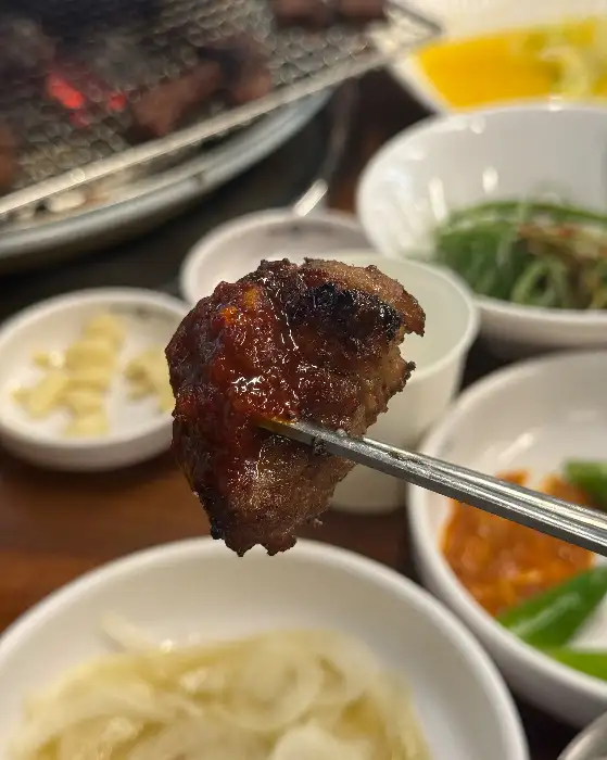 집게로 집은 잘 익은 돼지갈비 조각