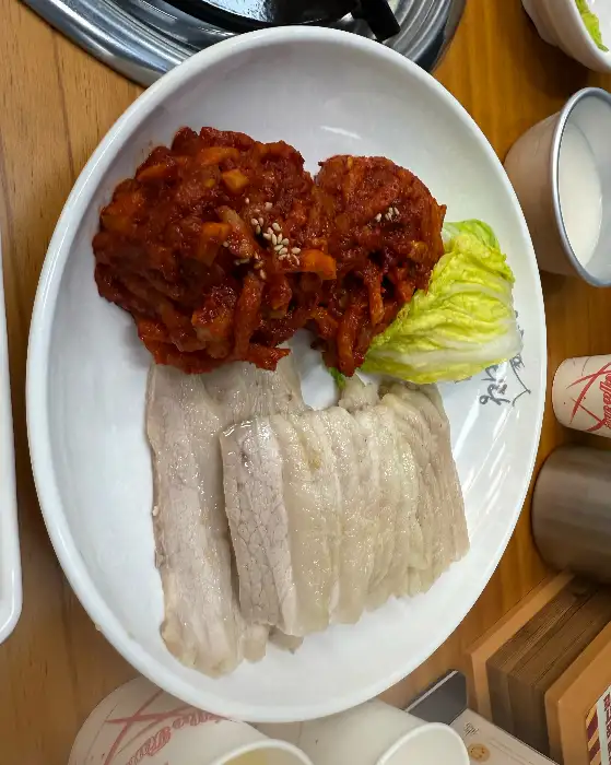 보쌈과 김치, 그리고 쌈채소가 플레이트에 담긴 모습