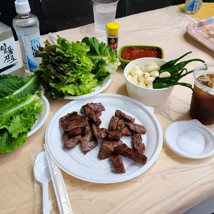 신선한 쌈 채소와 양념, 마늘, 고추 등 푸짐한 밑반찬 모습.