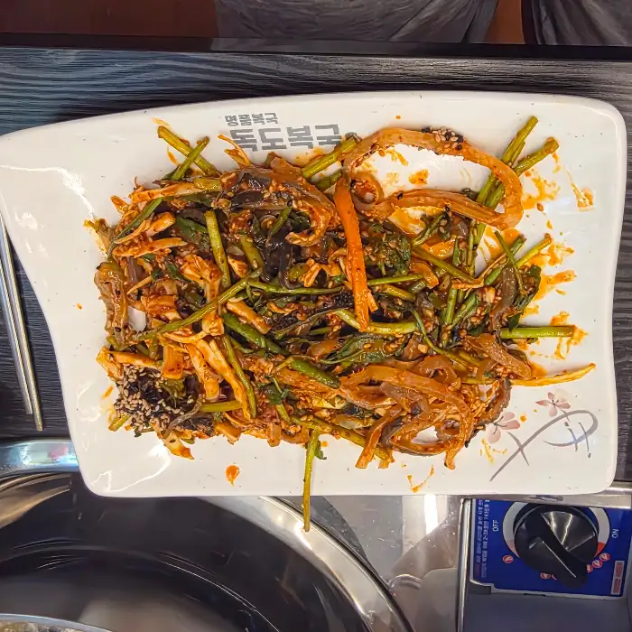 새콤달콤하게 무쳐진 복껍질무침이 큼직한 접시에 담겨 있습니다.