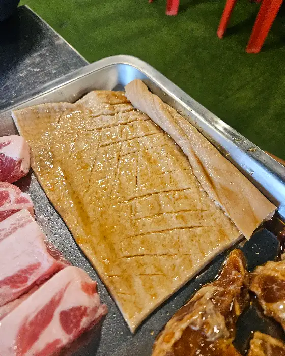 한쪽에는 도톰한 껍데기가, 다른 한쪽에는 살코기가 두툼한 삼겹살이 준비되어 있다. 껍데기에 칼집이 먹음직스럽게 나 있다.