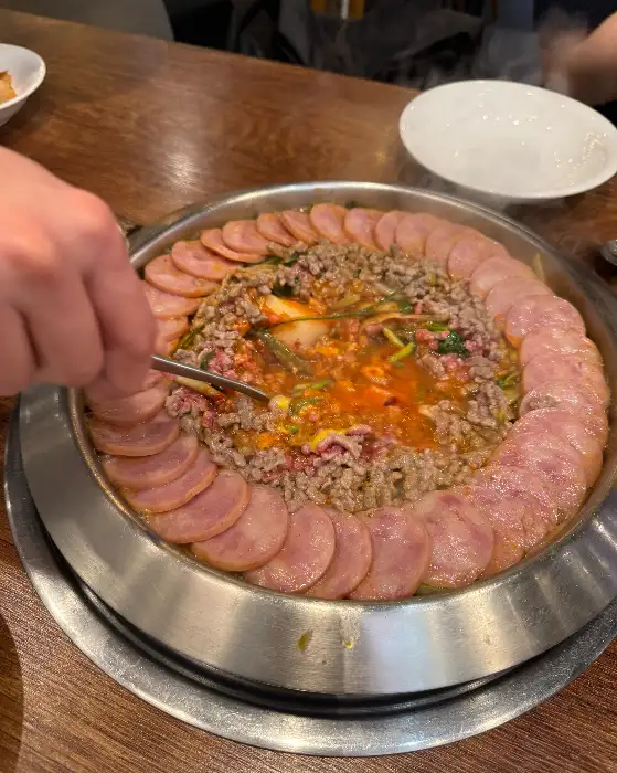 국자를 이용해 부대찌개를 젓는 모습