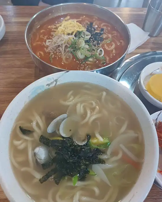 테이블 위에 놓인 두 그릇의 칼국수와 반찬