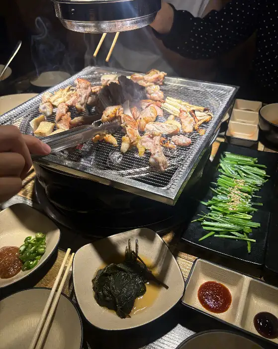 잘 차려진 밑반찬과 숯불구이 준비 모습