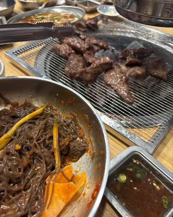 비빔냉면과 숯불에 구워지고 있는 고기
