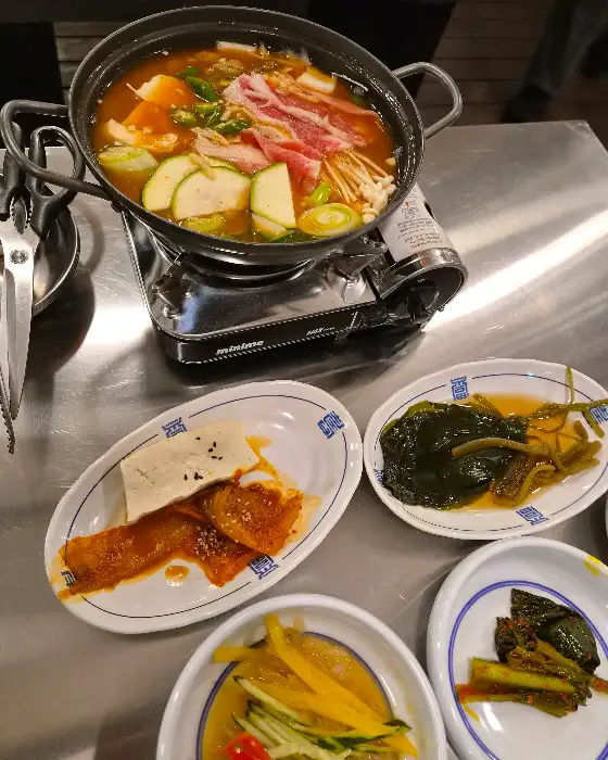 테이블 위에서 끓고 있는 된장찌개 전골과 여러 가지 반찬들