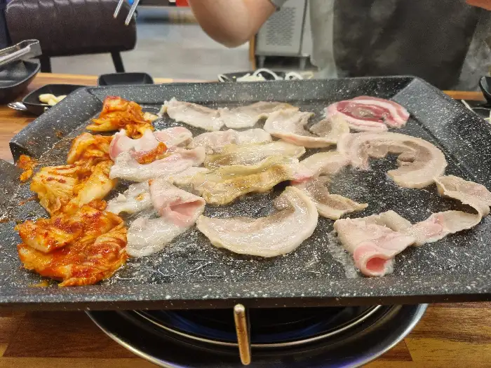 불판 위에서 익어가는 대패삼겹살과 김치