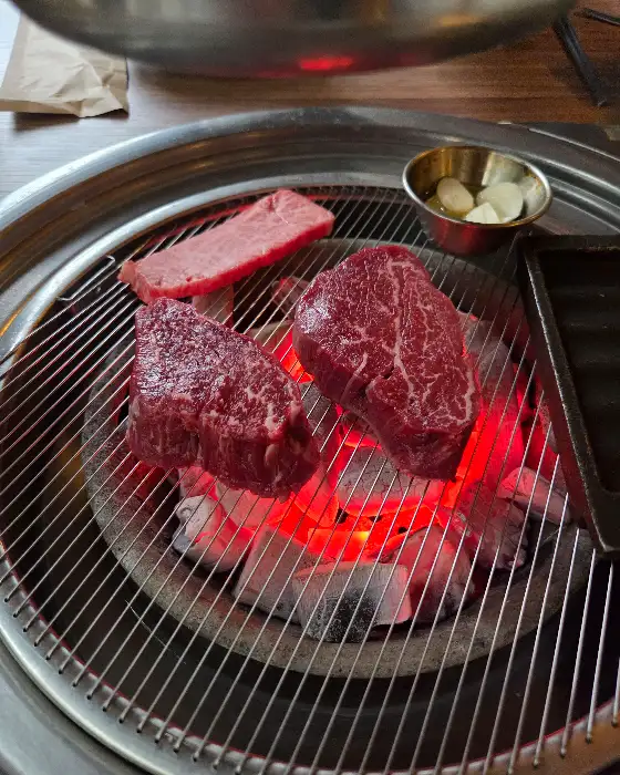 숯불 위에서 맛있게 구워지는 스테이크 같은 소고기