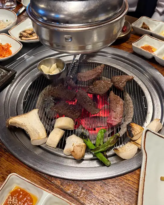 숯불 위에서 다양한 부위의 고기, 버섯, 고추가 구워지고 있는 모습