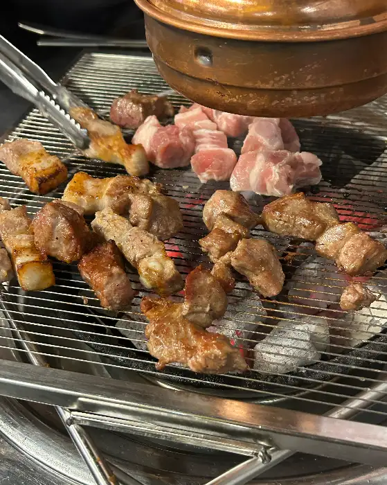 잘 익은 오겹살 한 점을 집어드는 모습