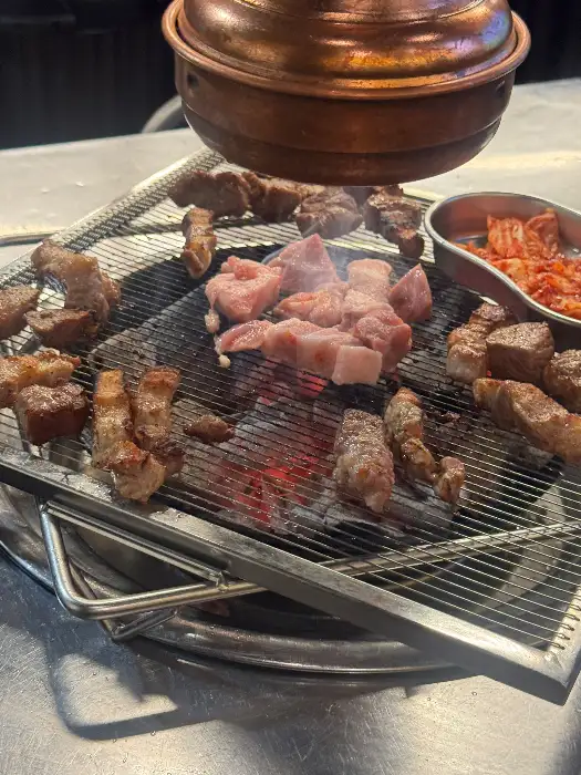 화로 위에서 여러 부위의 고기가 동시에 익고 있는 모습