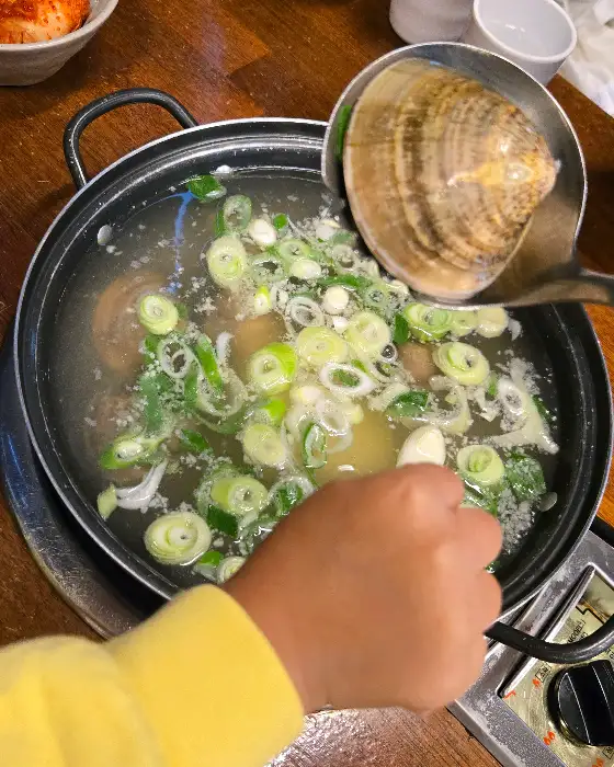 국자가 백합을 건져 올리는 모습. 국물과 함께 건져 올려지고 있다.