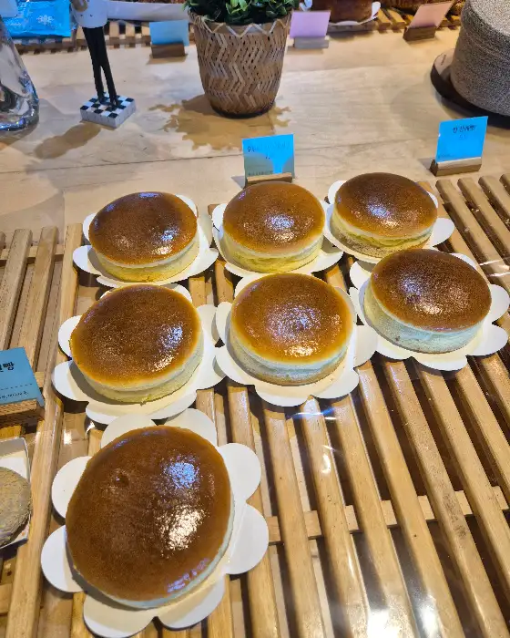 진열대에 가지런히 놓인 여러 개의 소금빵. 빵 겉면에 황금빛 윤기가 돌고, 윗면은 먹음직스럽게 구워져 있다.