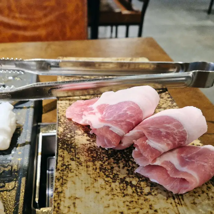 직원이 집게와 가위를 이용해 먹기 좋게 고기를 자르고 있는 모습